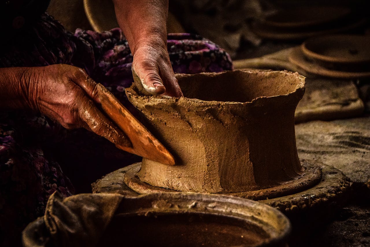 Detailed view of hands shaping pottery clay, highlighting traditional craftsmanship skills.